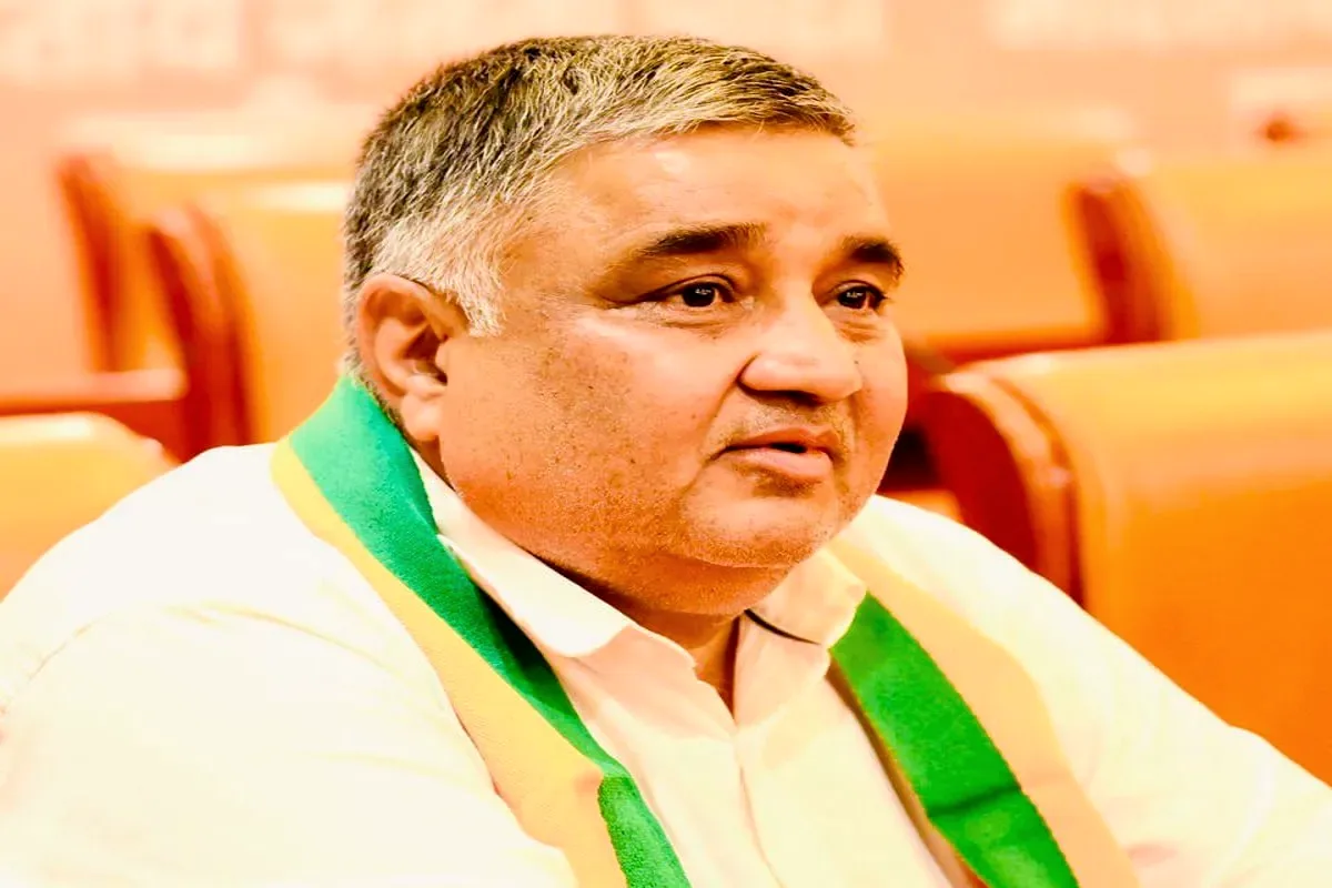 Rajesh Agrawal wearing a party scarf, seated in an assembly hall